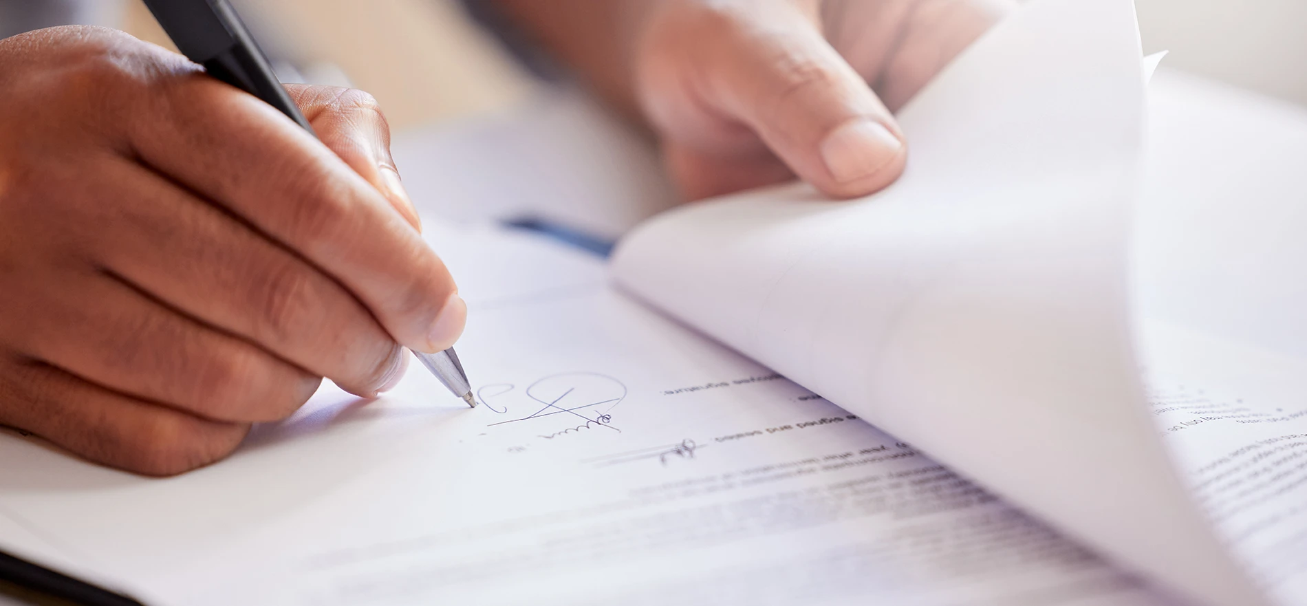 Close-up of a person signing a licensing contract with a pen